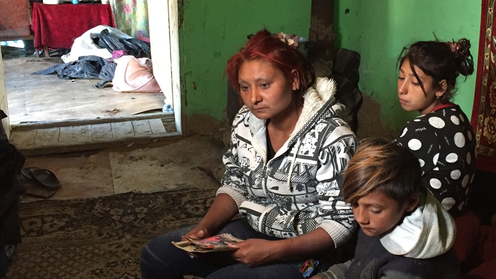 Iboya Popp holding photos of her murdered husband, David Popp [Al Jazeera]