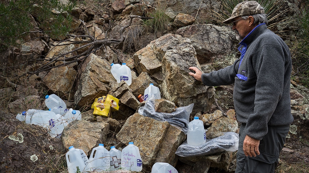 Glinski points to water left by human rights groups for migrants crossing the border [Patrick Strickland/Al Jazeera]