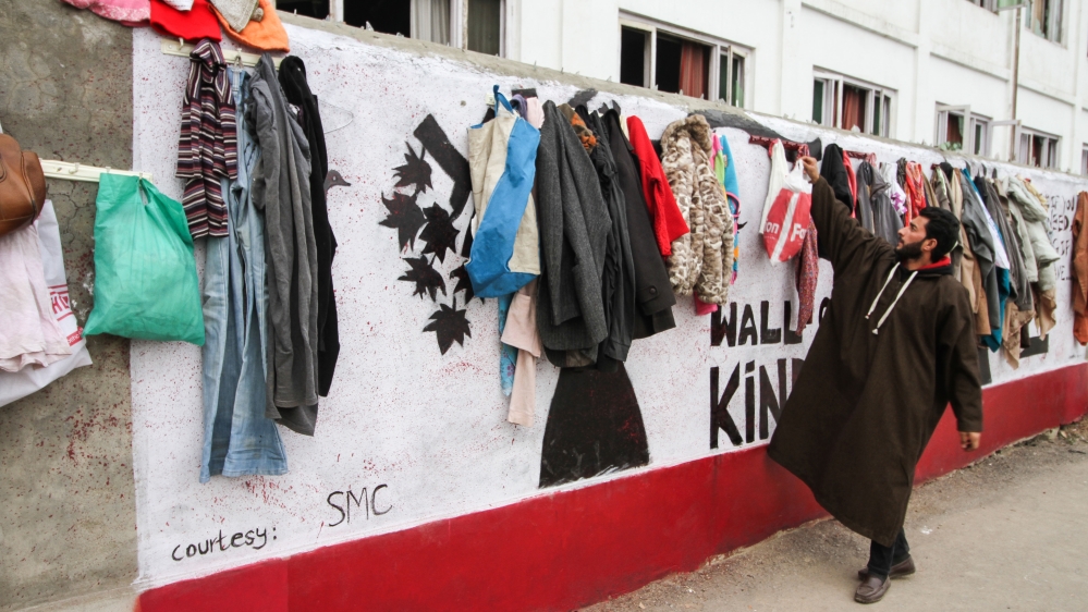 In Srinagar, a young Kashmiri man hangs clothes for people in need [Sameer Mushtaq/Al Jazeera]