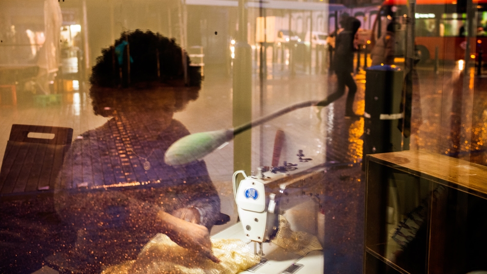 Beatrice, seen in the reflection of her shop window on Ridley Road Market [Jose Sarmento Matos/Al Jazeera]