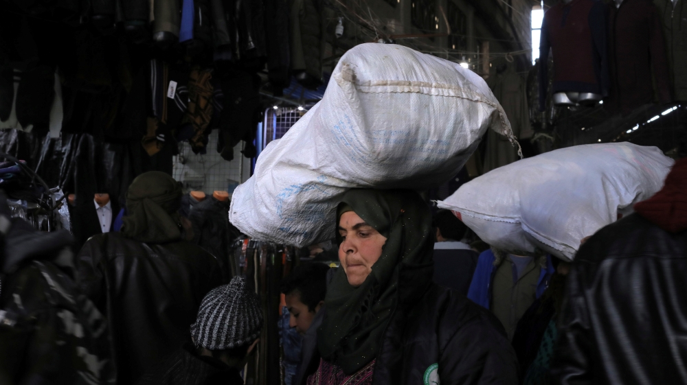 A woman holds a bag on her head at a souk in Manbij city