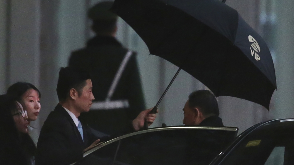 Kim Yong Chol, right, a North Korean senior ruling party official and former intelligence chief, is shielded with an umbrella as he arrives at the VIP terminal of the Beijing International airport in