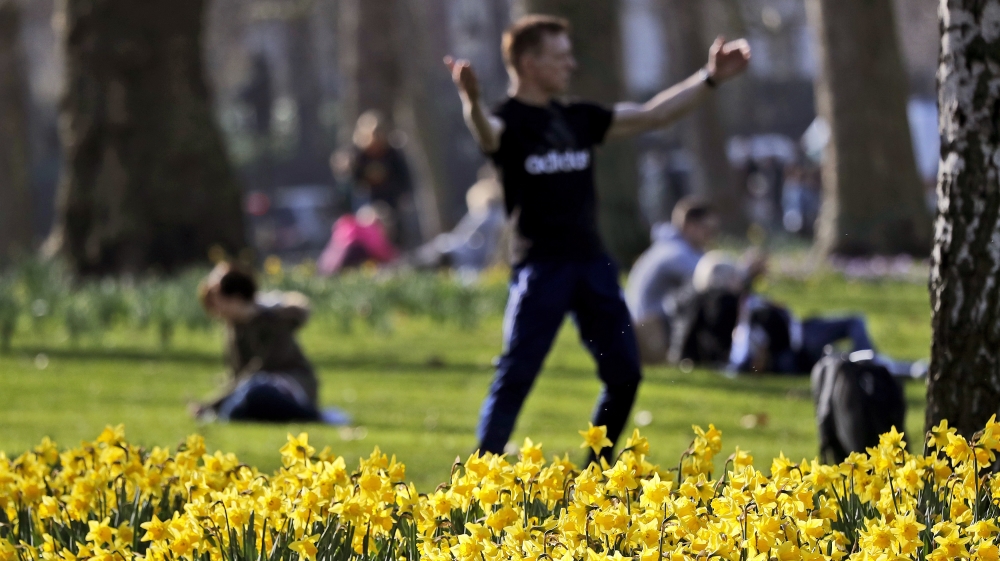 People enjoy their lunch break in a park during a sunny day as daffodils bloom in London, Friday, Feb. 22, 2019