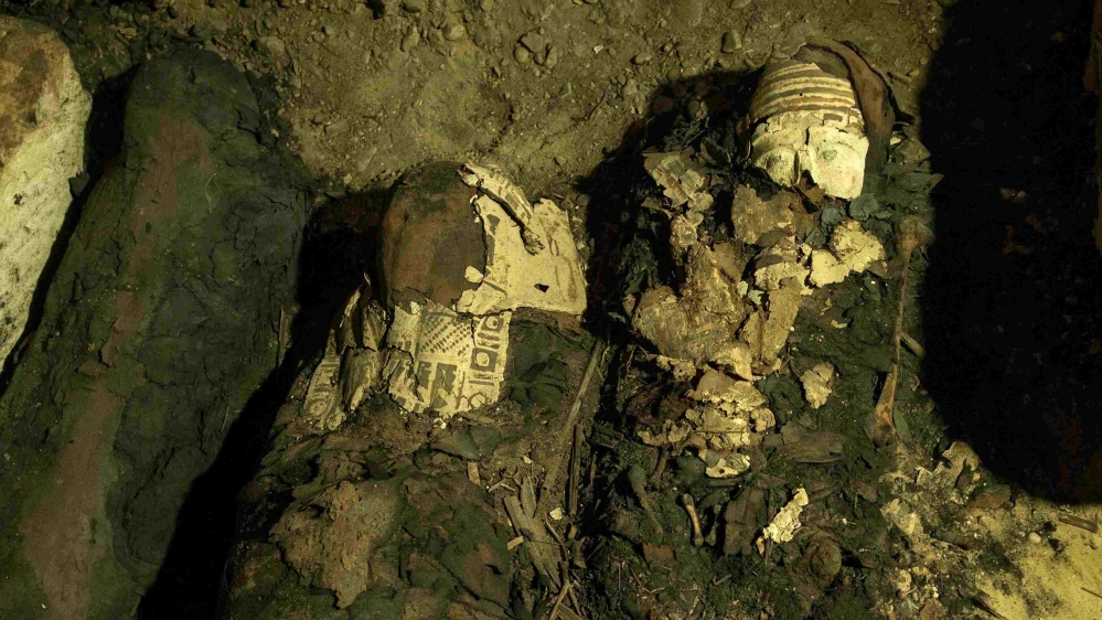 Mummy cases lie in a recently discovered burial chamber in the desert province of Minya [Roger Anis/AP]