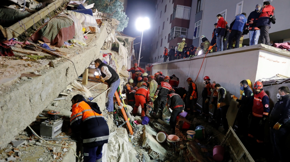 Rescue workers search for survivors at the site of the collapsed building [Umit Bektas/Reuters]