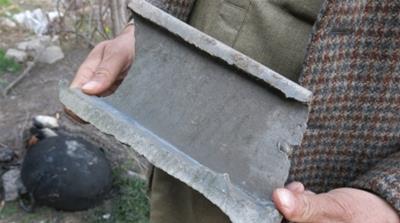 A villager shows a piece of shrapnel from one of the Indian bombs [Asad Hashim/Al Jazeera]