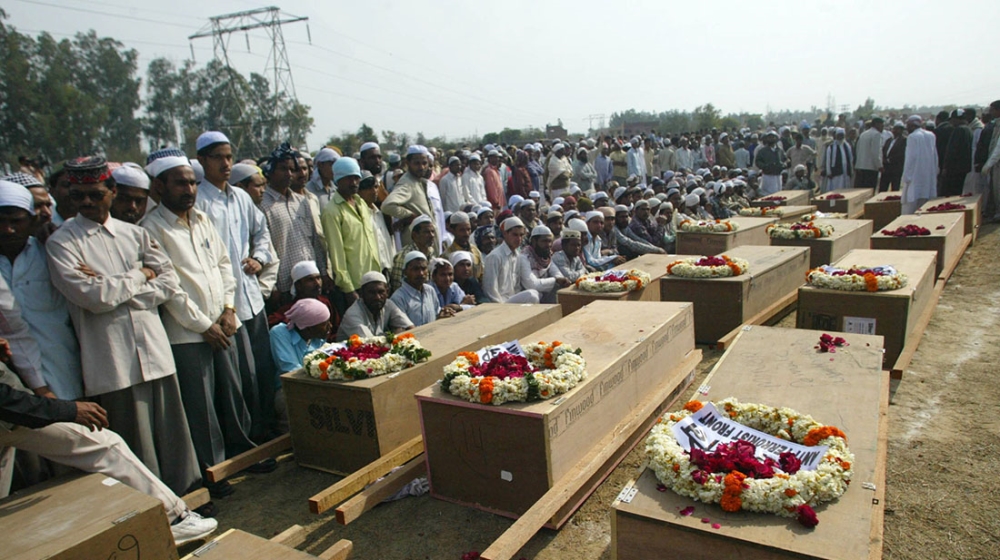 People look on at the mass burial of the unidentified bodies of the victims of Samjhauta Express Train attack in Panipat, India. [Mustafa Quraishi/The Associated Press]