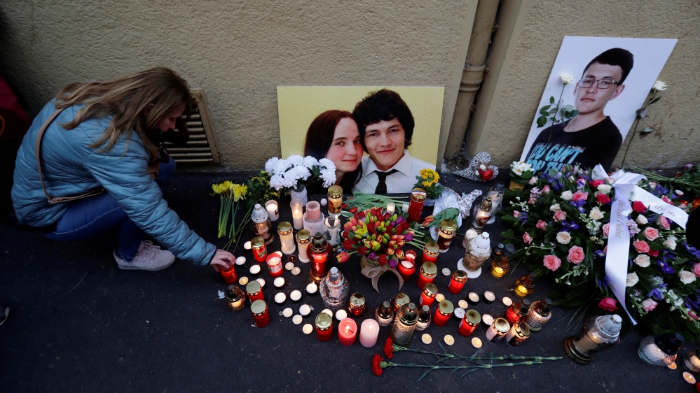 A woman kneels by a memorial on the first anniversary of the murder in Bratislava [David W. Cerny/Reuters]