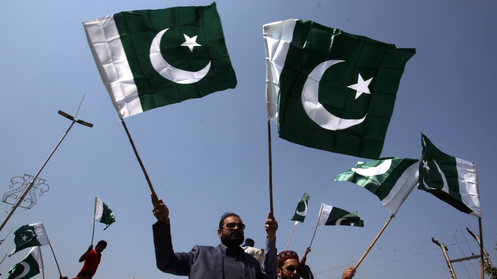 People carry national flags as they celebrate, after Pakistan shot down two Indian military aircrafts, in Lahore