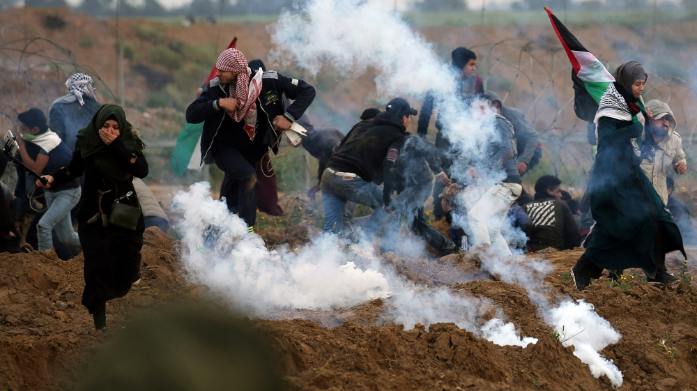Palestinian demonstrators run away from teas gas fired by Israeli forcers during a protest at the Israel-Gaza border fence, in the southern Gaza Strip