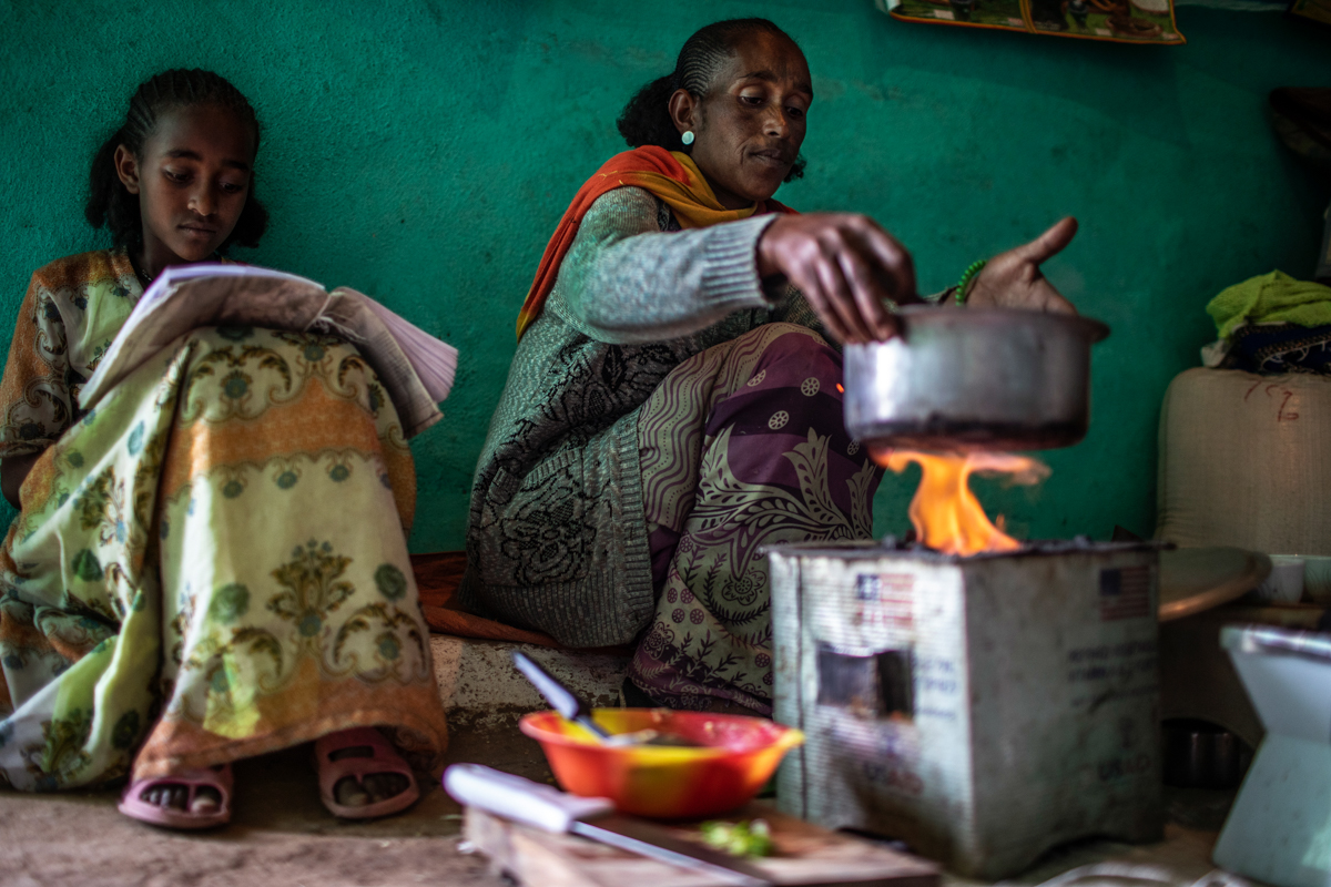 Birhan T/medhin (right) cooks a split pea dish using rations she received from the USAID-funded Joint Emergency Operation Program (JEOP) at her home in Mezutey, Hawzen district, in Misraqawi Zone, Tig