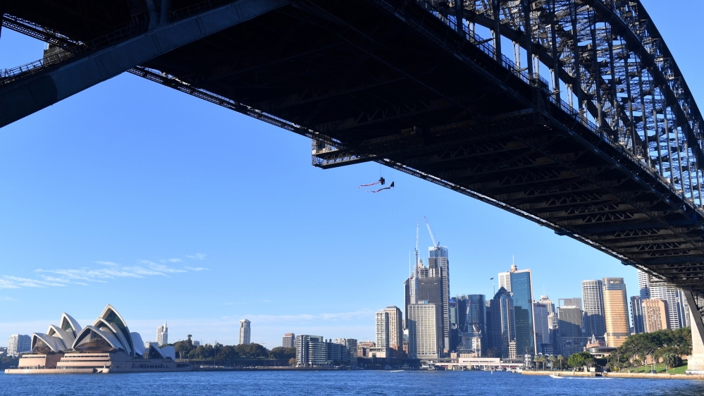 Greenpeace activists can be seen suspended from the undercarriage of the Sydney Harbour Bridge in Sydney [AAP Image/Dean Lewins/via Reuters]