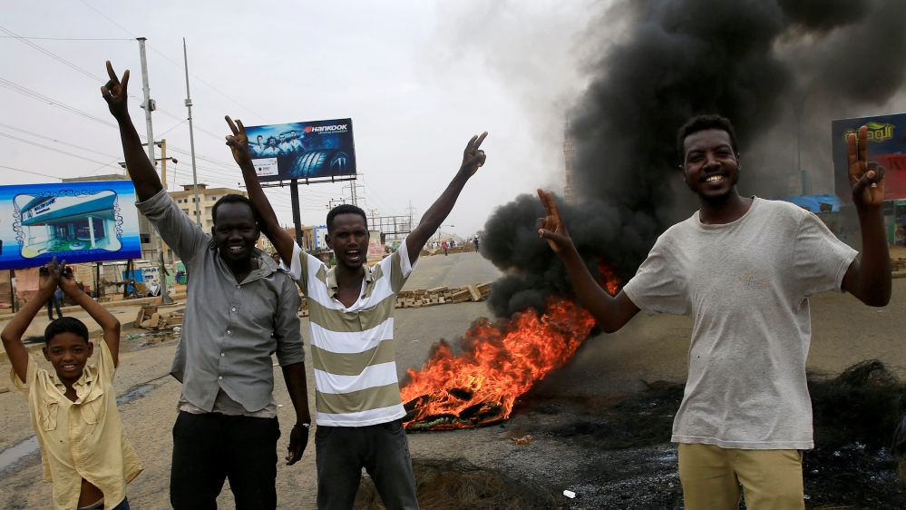 Sudanese protesters gesture near burning tyres used to erect a barricade on a street, demanding that the country''s Transitional Military Council handover power to civilians, in Khartoum