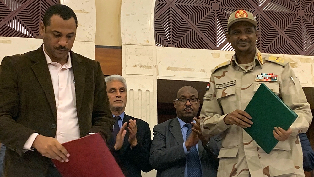 Sudanese deputy chief of the ruling miliary council Mohamed Hamdan Dagalo (R) and protest movement Alliance for Freedom and Changes leader Ahmad al-Rabiah stand after inking an agreement before Africa