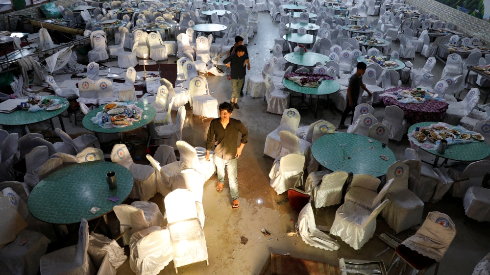 Workers inspect a damaged wedding hall after a blast in Kabul, Afghanistan