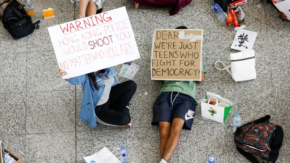 Anti-government demonstrators sit in a designated area of the arrival hall of the airport in Hong Kong after police and protesters clashed the previous night