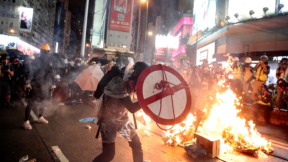 A protestor uses a shield to cover himself as he faces policemen in Hong Kong, Saturday, Aug. 31, 2019. Protesters and police are standing off in Hong Kong on a street that runs through the bustling C