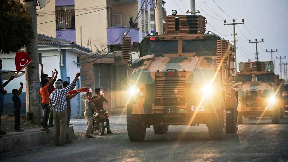 Shortly after the Turkish operation inside Syria had started, local residents cheer and applaud as a convoy of Turkish forces vehicles is driven through the town of Akcakale, Sanliurfa province, south