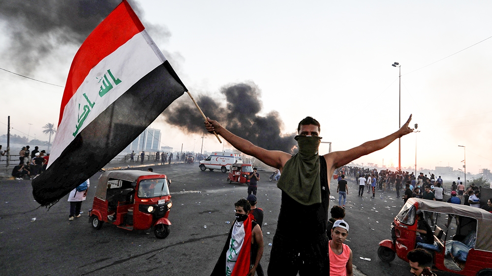 A demonstrator holds an Iraqi flag at a protest after the lifting of the curfew, following four days of nationwide anti-government protests that turned violent, in Baghdad, Iraq October 5, 2019. REUTE