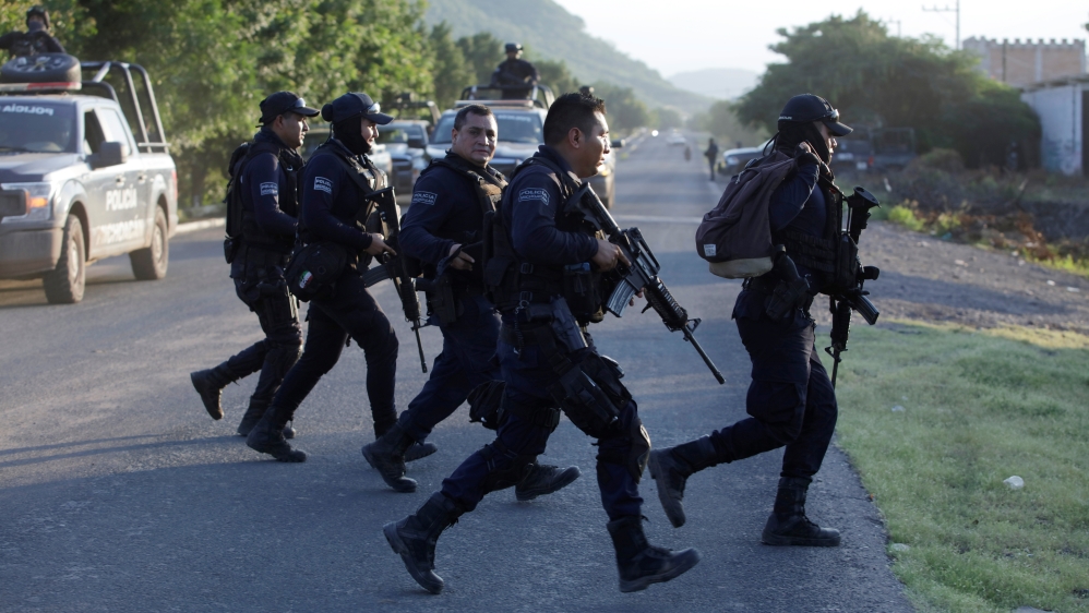 Police officers patrol at a road after fellow police officers were killed during an ambush by suspected cartel hitmen in El Aguaje