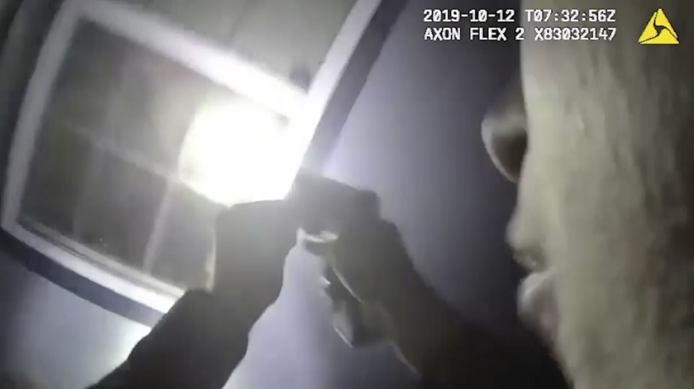 In this Saturday, Oct. 12, 2019, image made from a body camera video released by the Fort Worth Police Department an officer shines a flashlight into a window in Fort Worth, Texas. A black woman was f