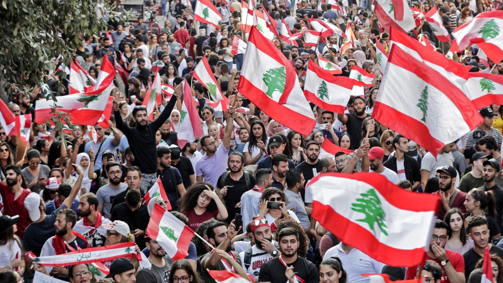 Lebanese protesters wave national flags during demonstrations to demand better living conditions and the ouster of a cast of politicians who have monopolised power and influence for decades, on Octobe
