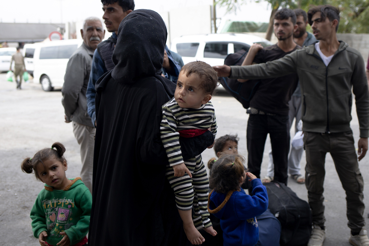 Families wait to board designated buses at the Karkamis border crossing to return to their homes across southern Turkey