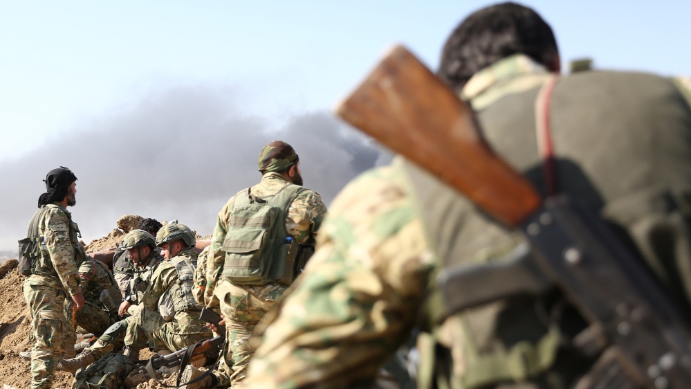 Turkish-backed Syrian rebels and Turkish soldiers watch as smoke billows from the border town of Ras al-Ain on October 12, 2019