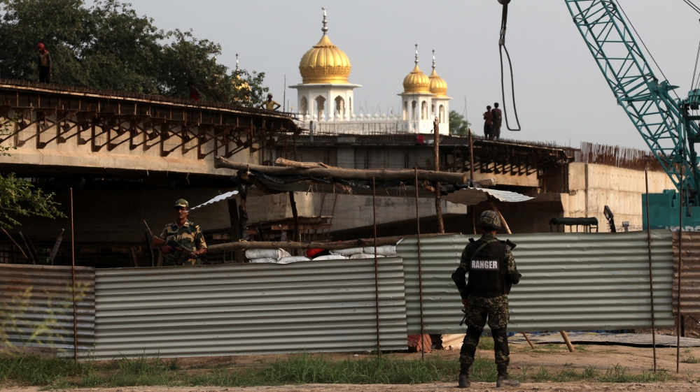 Pakistan''s paramilitary soldier and Indian soldier stand guard across steel sheets at the construction site of a bridge leading in Kartarpur