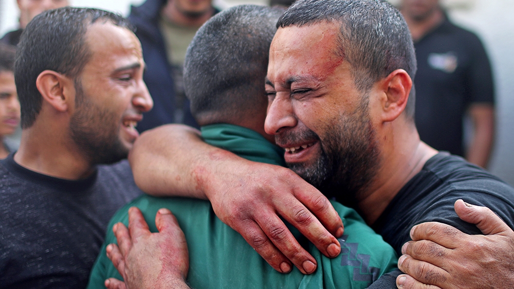 A Palestinian man, stained with the blood of his relative, is comforted as he reacts at Shifa hospital in Gaza City November 13, 2019. REUTERS/Mohammed Salem