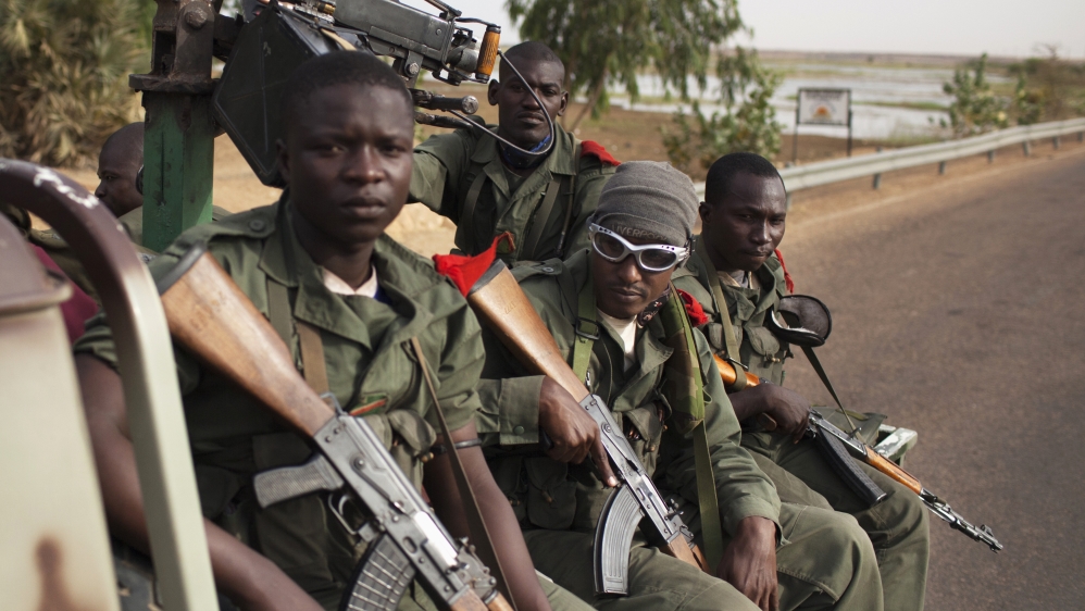 Malian soldiers ride in the back of a military pickup truck in Gao