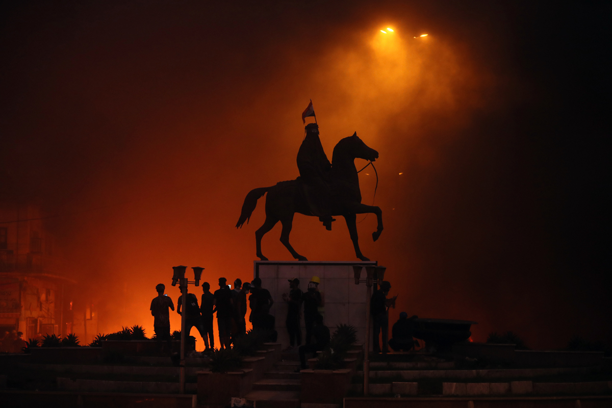 Anti-government protesters set fire while security forces fired live ammunition and tear gas near the state-run TV in Baghdad, Iraq, Monday, Nov. 4, 2019. (AP Photo/Hadi Mizban)