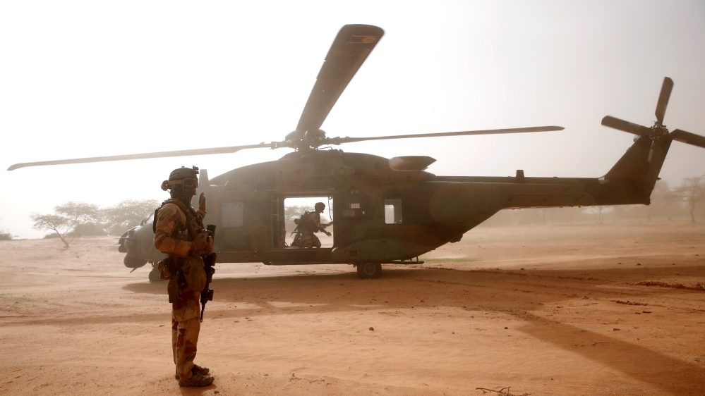 A French soldier stands guards in front of an NH90 Caiman military helicopter during Operation Barkhane in Ndaki