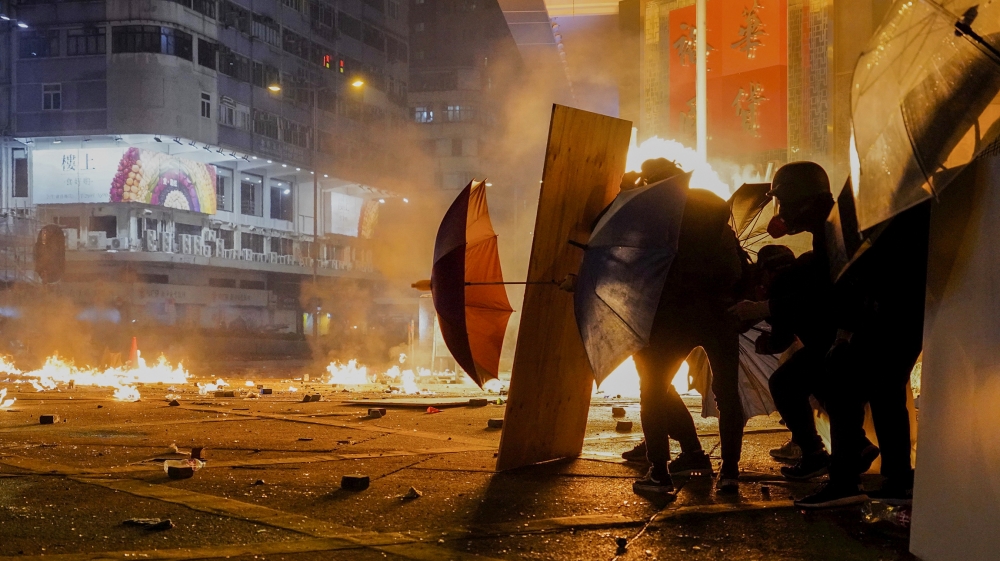 Protestors react as police fire tear gas in the Kowloon area of Hong Kong, Monday, Nov. 18, 2019. As night fell in Hong Kong, police tightened a siege Monday at a university campus as hundreds of anti