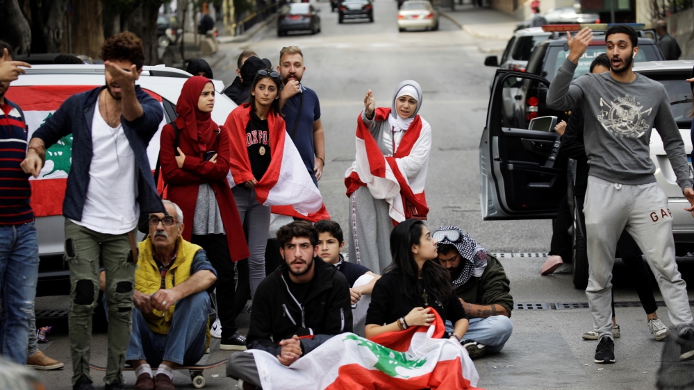 Protesters gesture towards a driver at a roadblock during ongoing anti-government demonstrations in Beirut