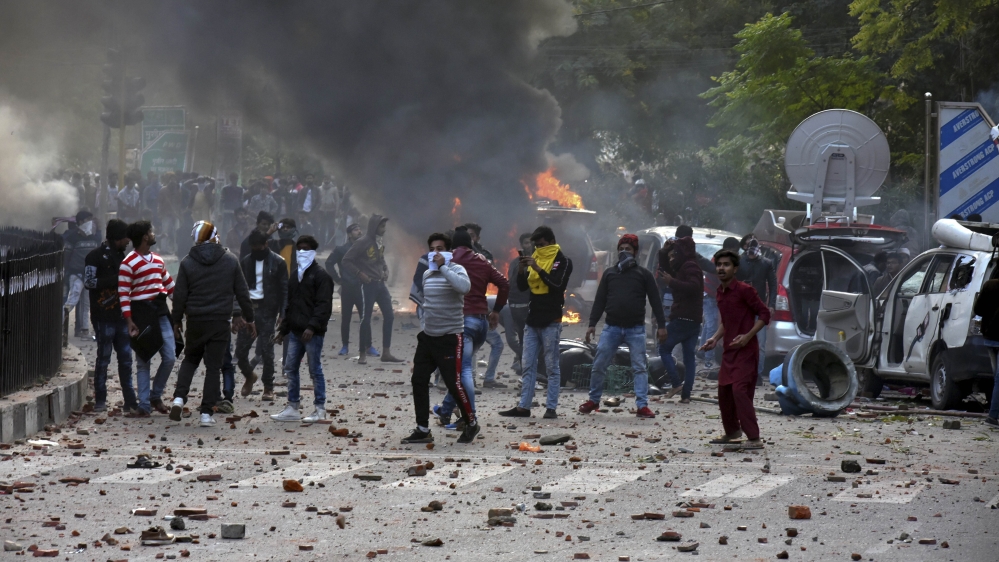 People throw stones at police as broadcast vans of television channels go up in flames during protests against India''s new citizenship law in Lucknow, India, Thursday, Dec. 19, 2019