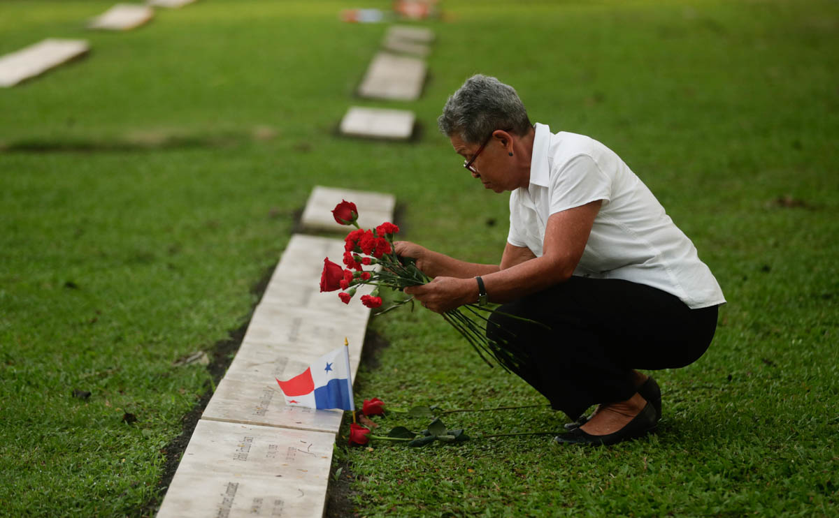 A woman places flowers on the grave of a person who died during the 1989 U.S. military invasion that ousted Panamanian strongman Manuel Noriega, on the 30th anniversary of the invasion in Panama City,