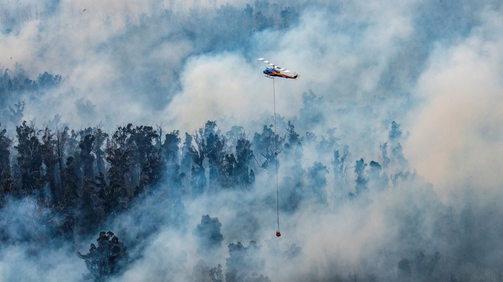 This handout photo taken on December 29, 2019 and received on December 30 from Victoria''s Department of Environment, Land, Water and Planning (DELWP) shows a helicopter dumping water on a fire in Vict