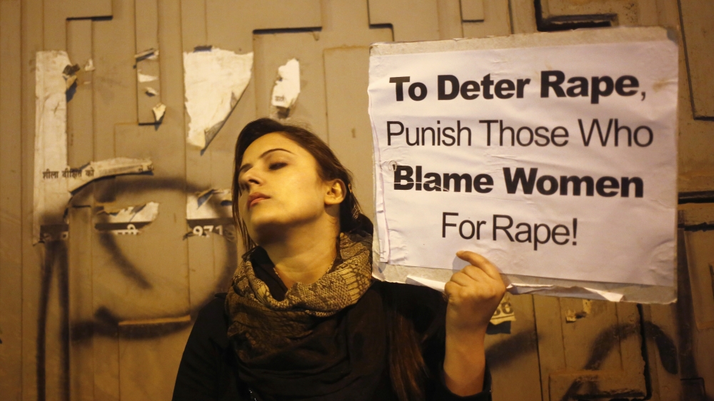 A demonstrator holds a placard as she attends a candlelight vigil to mark the first anniversary of Delhi gang rape, in New Delhi