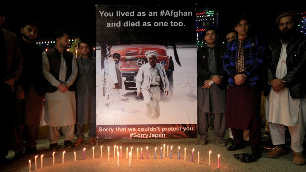 Men light candles in front of the portrait of Japanese doctor Tetsu Nakamura, who was killed in today''s attack in Jalalabad, Afghanistan