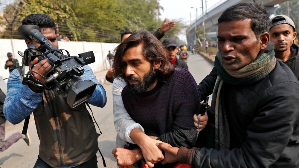 Wounded man is helped after an unidentified man opened fire during a protest against a new citizenship law outside the Jamia Millia Islamia university in New Delhi