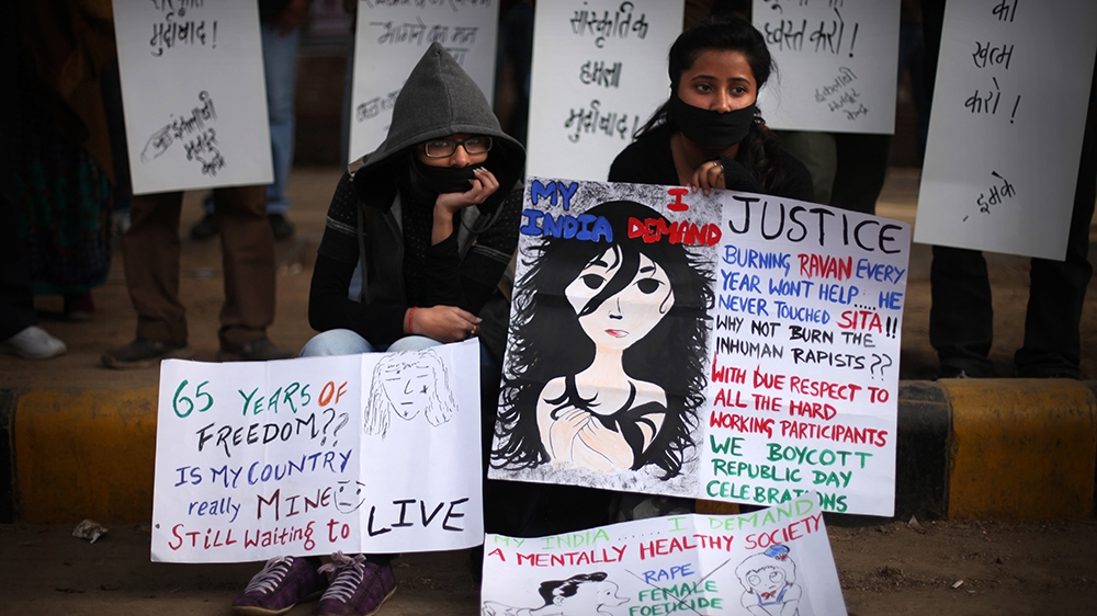 Indian protesters sit on a sidewalk with placards during a protest after the death of a young woman who was recently gang-raped in a moving bus in New Delhi, India, Sunday, Dec. 30, 2012. The young wo