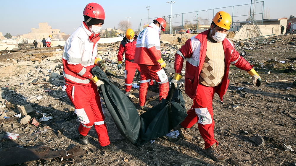 Members of the International Red Crescent collect bodies of victims around the wreckage after an Ukraine International Airlines Boeing 737-800 carrying 176 people crashed near Imam Khomeini Airport in