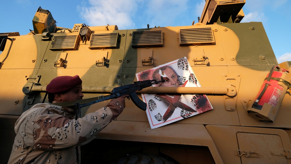 A member of Libyan National Army (LNA) commanded by Khalifa Haftar, points his gun to the image of Turkish President Tayyip Erdogan hanged on a Turkish military armored vehicle, which LNA said they co