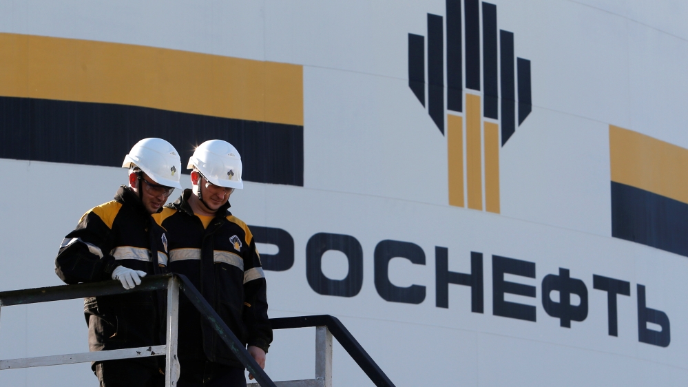 Workers stand next to logo of Russia''s Rosneft oil company at central processing facility of Rosneft-owned Priobskoye oil field outside Nefteyugansk