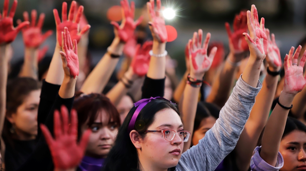 Women raise their hands as they protest against gender violence and femicide in Puebla