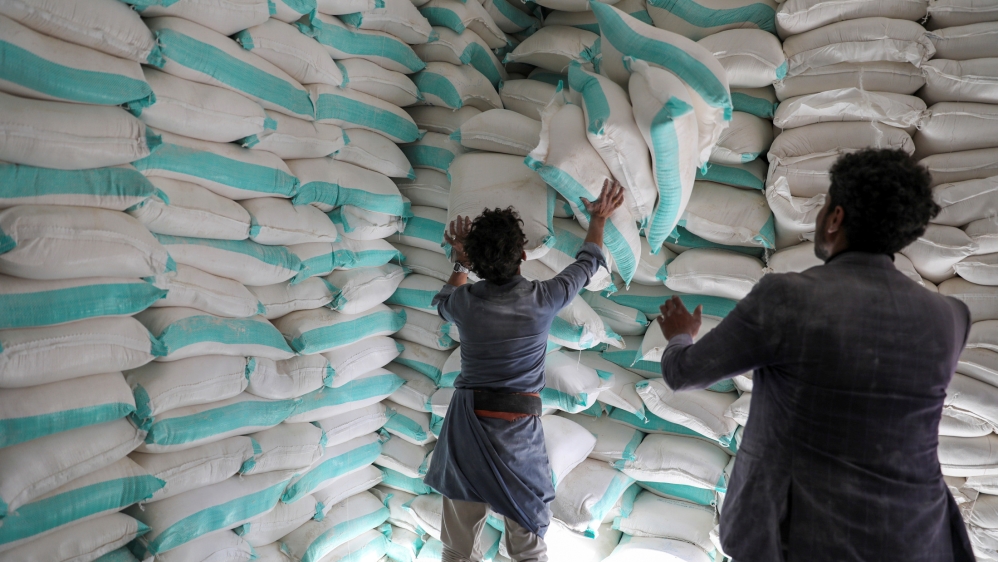 Workers handle sacks of wheat flour at a World Food Programme food aid distribution center in Sanaa