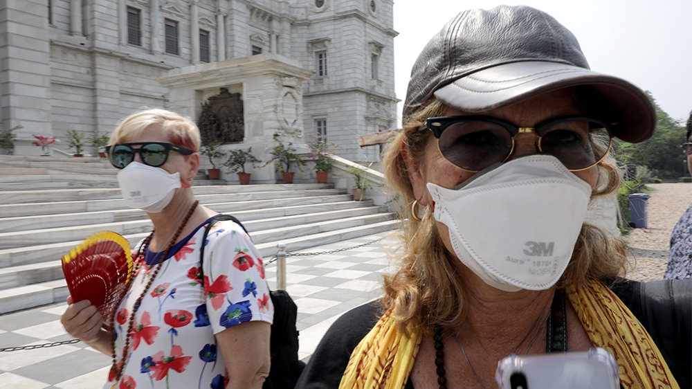 epa08302972 Tourists wear protective face mask as they wait near Victoria Memorial in Kolkata, India, 18 March 2020. The Bengal government has issued advisory notices for public places, to reduce crow