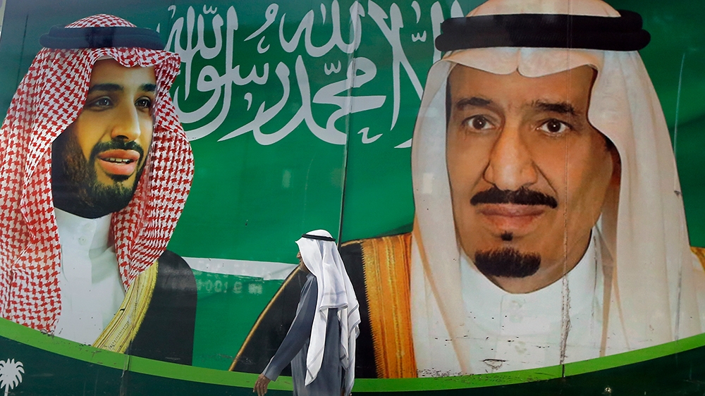 A man walks past a banner showing Saudi King Salman, right, and his Crown Prince Mohammed bin Salman, outside a mall in Jiddah, Saudi Arabia, Saturday, March 7, 2020. (AP Photo/Amr Nabil)
