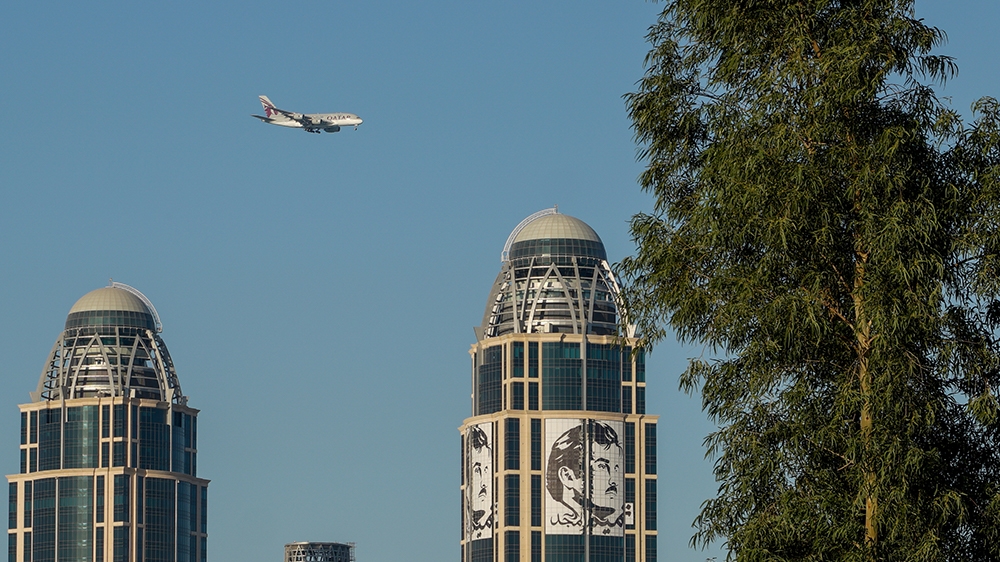 Qatar Airways plane flies past two skyscrapers in Doha, Qatar, March 07, 2020 [Sorin Furcoi/Al Jazeera]